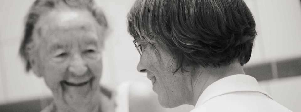 Ältere Dame lächelt eine andere Frau an