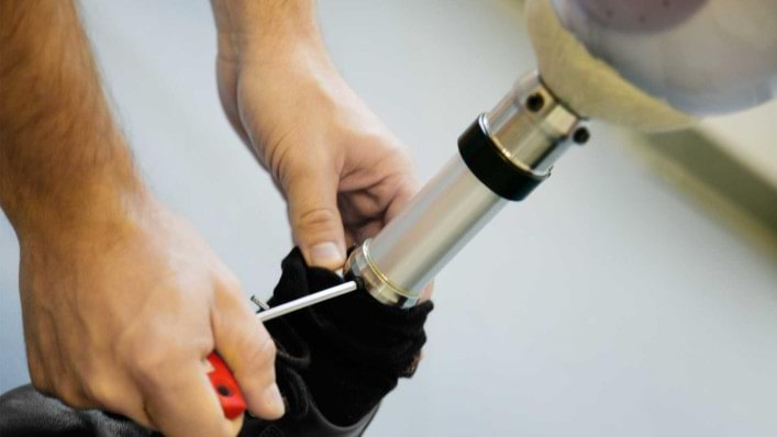 Hände schrauben an einem Prothesenfuß