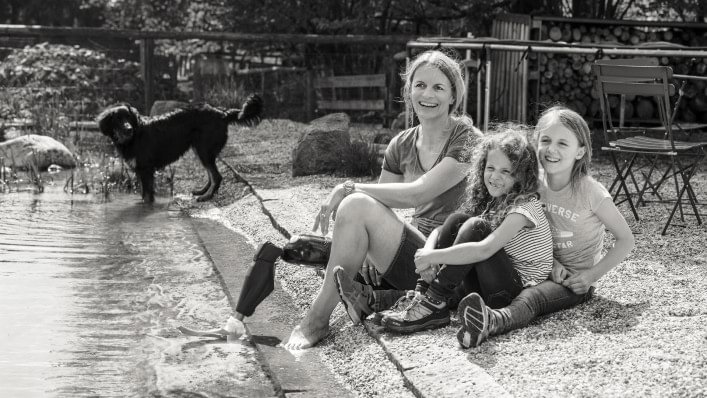 Kerstin mit ihrem Genium X3 sitzt mit ihren Töchtern am Wasser.